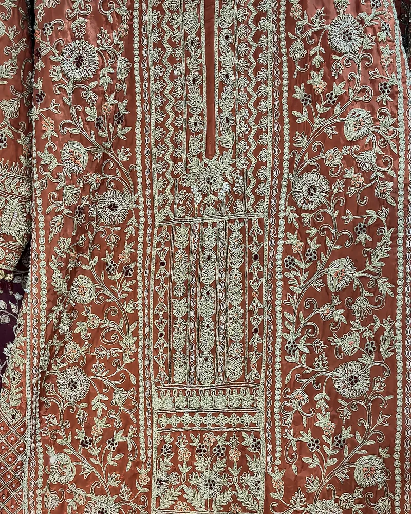 The front of a rust kurta embroidered from placket to hem in dabka, pearls and stones