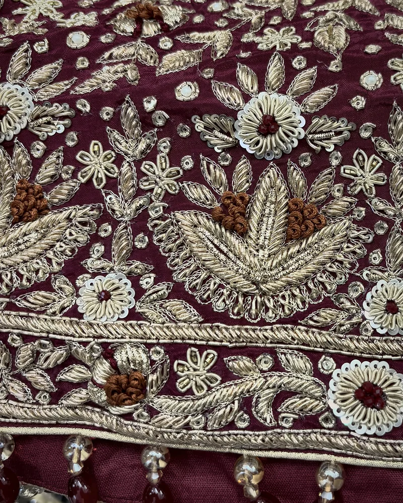 Lotus buta and border on wine in dabka, sequins and rust thread, above a row of beaded latkan